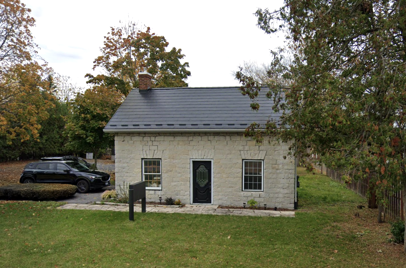 A small limestone dwelling with rear tail, gable roof, and regular fenestration pattern