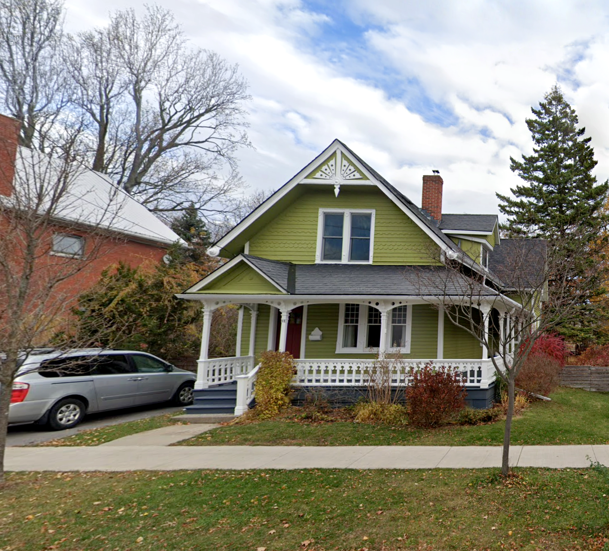 This rare surviving example of a late 19th century vernacular Carpenter Gothic frame house has intricate white dental work, a wrap around porch and green siding