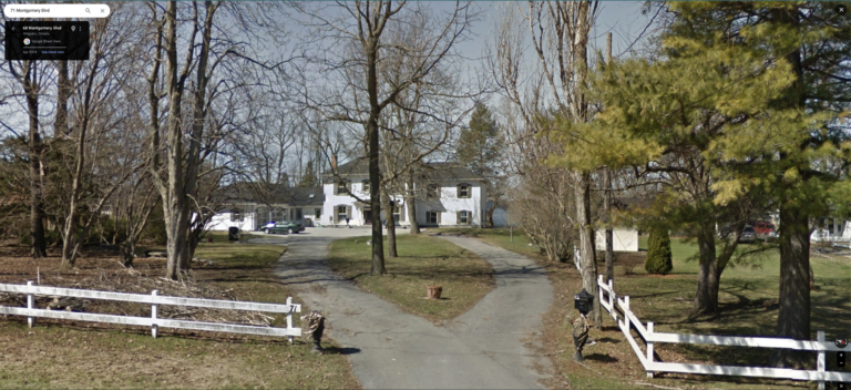 A grand old rural house with white siding, many windows all with shutters